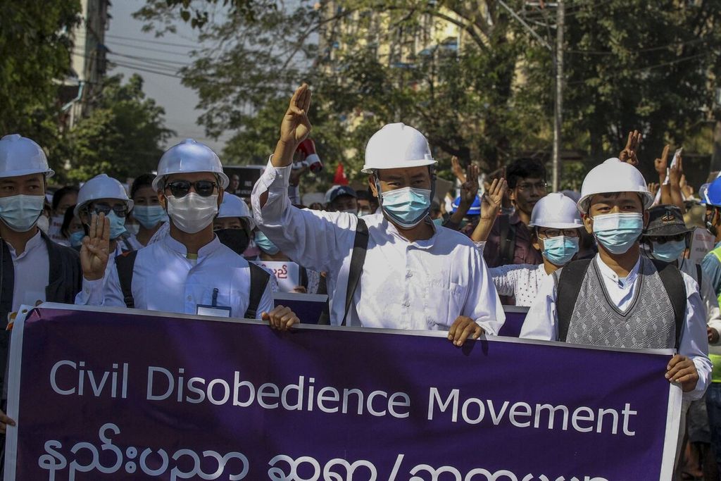 Para demonstran memberikan salam tiga jari sebagai isyarat perlawanan dan membawa spanduk bertuliskan gerakan pembangkangan sipil dalam unjuk rasa menentang kudeta militer di Yangon, Myanmar, 10 Februari 2021. 