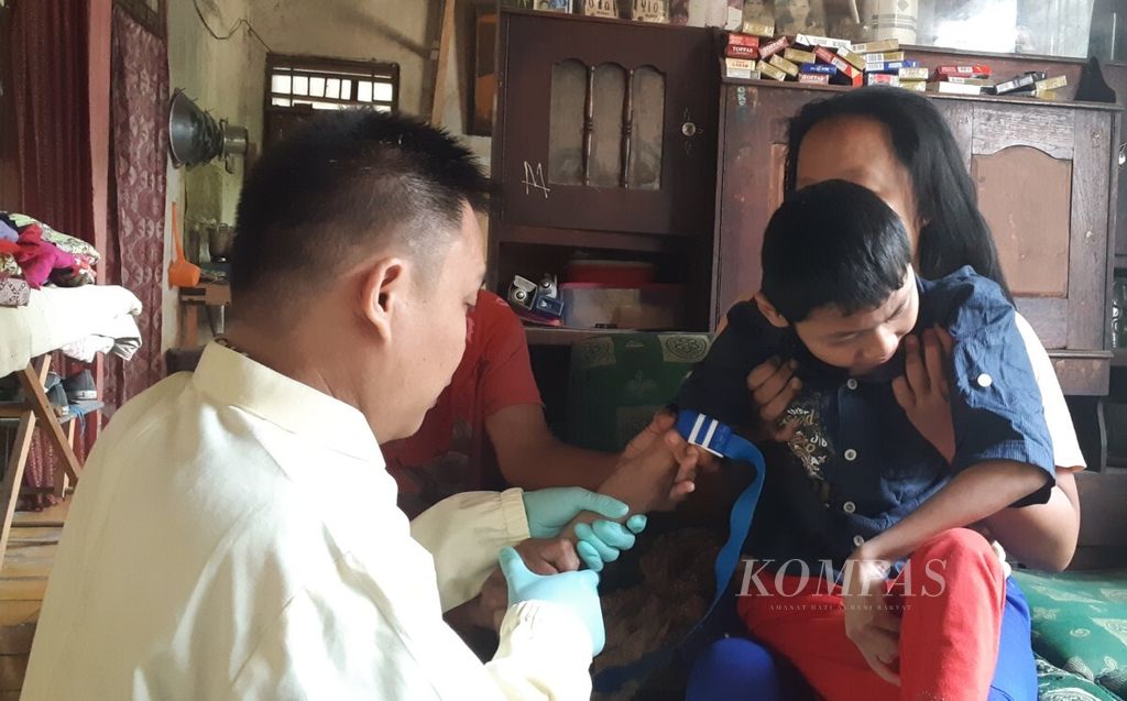 Petugas kesehatan mengambil sampel darah Ridho (12), anak penderita gangguan mental, di Desa Cinangka, Kabupaten Bogor, Kamis (20/9/2018). Gangguan mental yang dialami Ridho diduga salah satunya dipicu tingginya kadar timbal di lingkungan sekitarnya. 