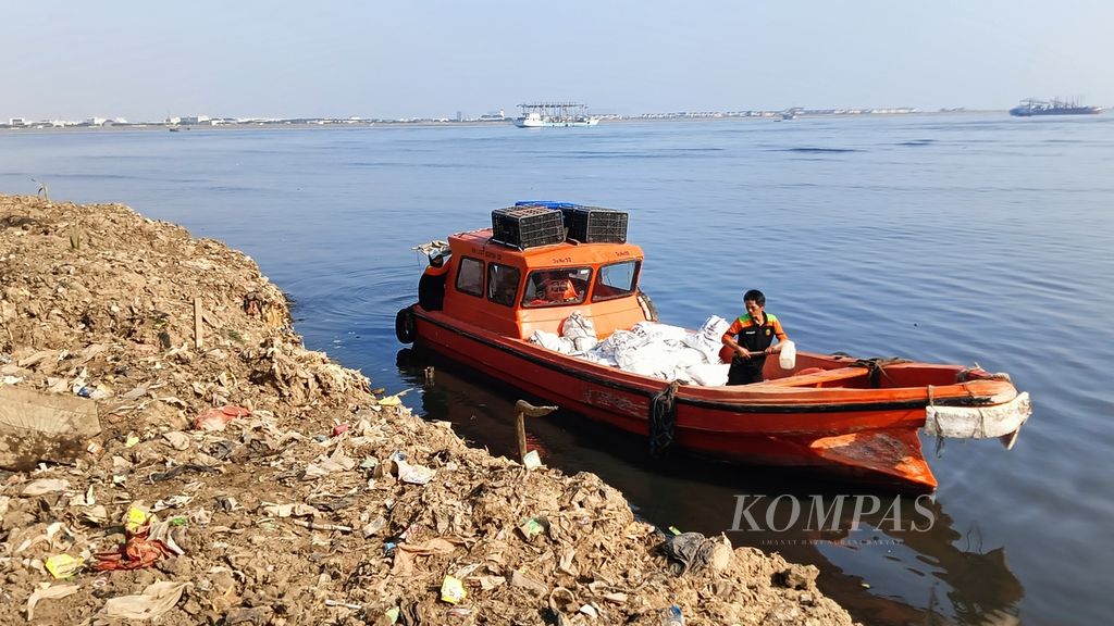 Sebuah kapal membawa sampah yang telah dikumpulkan di dalam karung di pesisir Muara Kali Adem, Penjaringan, Jakarta Utara, Sabtu (7/9/2024).