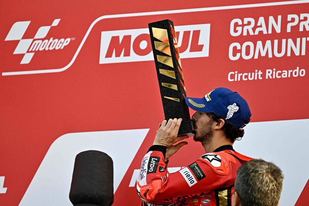 Pebalap Ducati Lenovo, Francesco Bagnaia, mencium trofi sebagai juara dunia setelah balapan utama MotoGP seri Valencia di Sirkuit Ricardo Tormo, Cheste, Spanyol, Minggu (26/11/2023).  