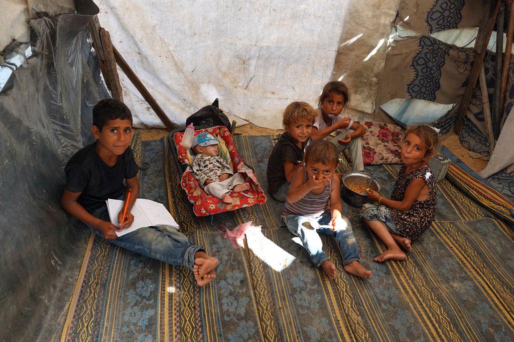 Lima anak Palestina berkumpul di tenda pengungsian mereka sambil makan persediaan makanan tersisa di kamp pengungsi Deir al-Balah, Jalur Gaza, Selasa (11/6/2024). 