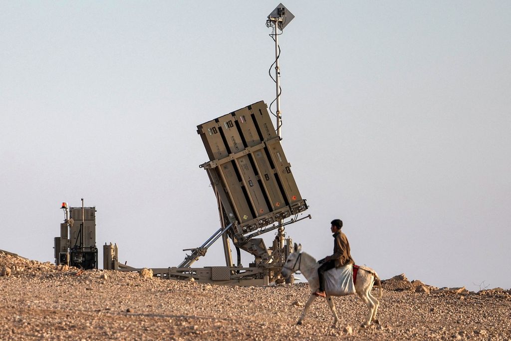 A boy riding a donkey passes near one of the Iron Dome missile defense system batteries in a village in the Negev desert, Israel, on Sunday (4/14/2024).