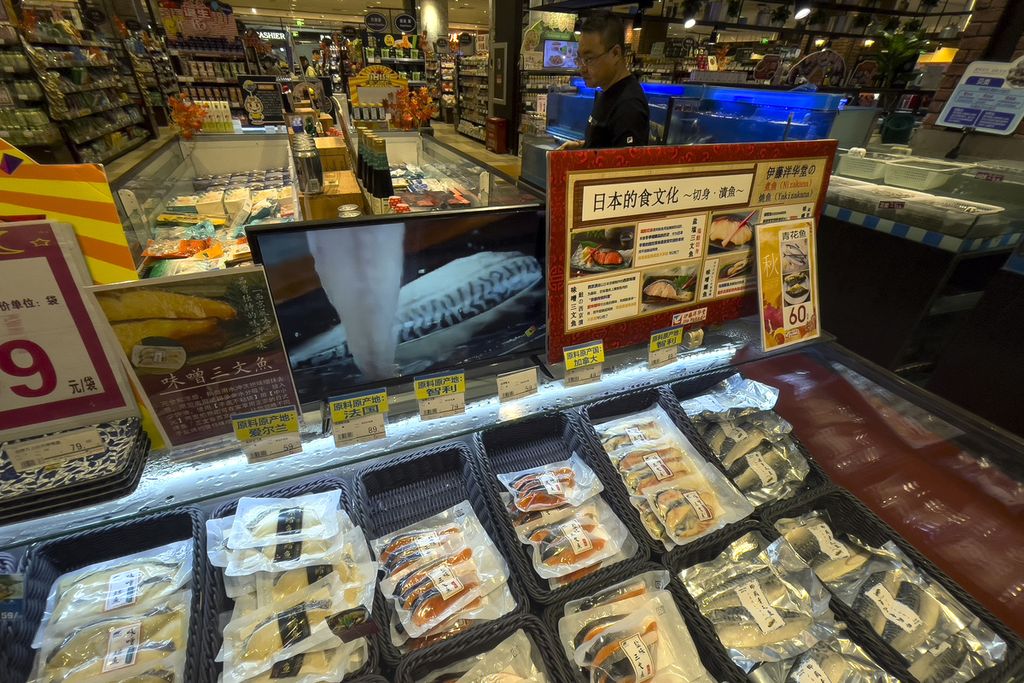 Seorang konsumen melihat kemasan makanan laut impor dari Chile, Perancis, dan Kanada di dekat monitor yang menunjukkan cara memasak ala Jepang di supermarket Jepang di Beijing, China, 24 Agustus 2023.  