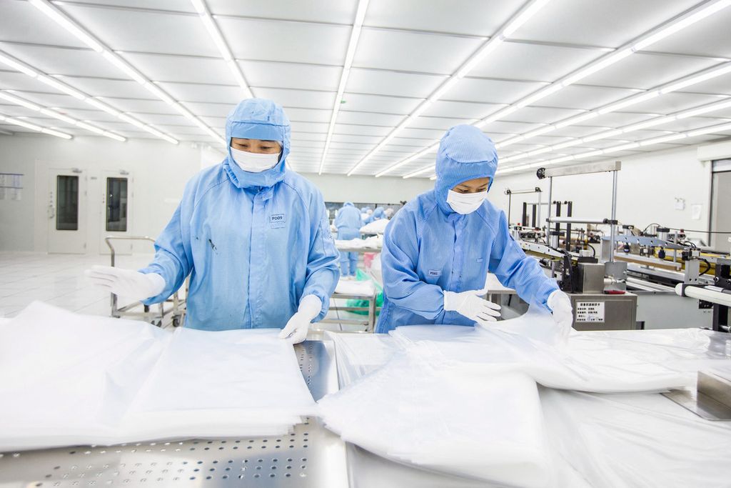 Para pekerja di pabrik di Haian, Provinsi Jiangsu, China, membuat material pembungkus paket semikonduktor pada 27 Februari 2023.