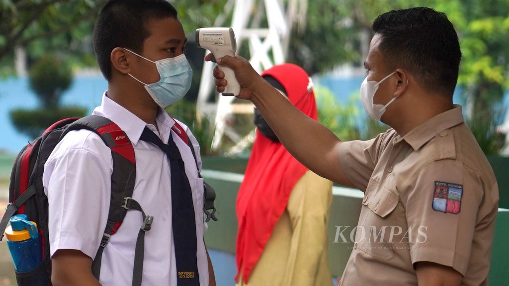 Pengukuran suhu tubuh siswa SMP Negeri 15 Kota Bogor, Jawa Barat, saat pelaksanaan uji coba pembelajaran tatap muka, Senin (31/5/2021).