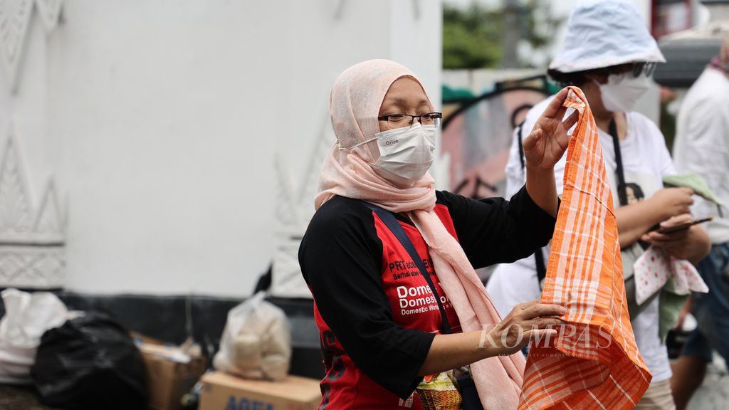 Pekerja rumah tangga (PRT) yang tergabung dalam Serikat PRT Tunas Mulia memakai kain serbet sebagai simbol protes saat menggelar aksi di Jembatan Kewek, Kotabaru, Yogyakarta, pertengahan Desember 2021.  