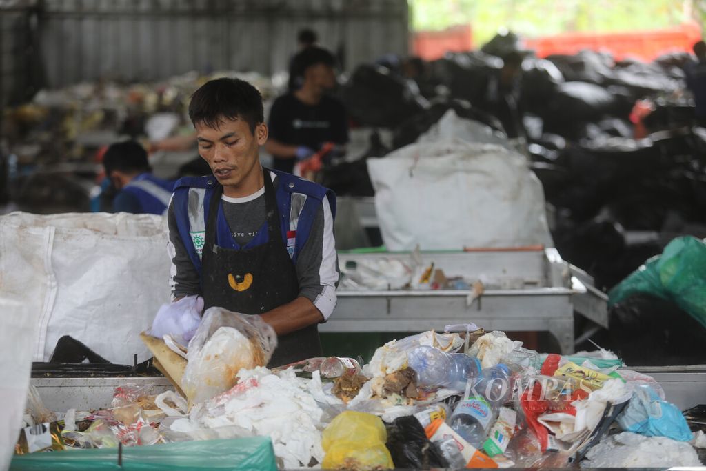 Pekerja memilah sampah organik dan anorganik dari korporat di bengkel produksi penyedia jasa pengolahan sampah Rumah Pemulihan Material (RPM) Waste4Change Bekasi 2.0 di kawasan Padurenan, Mustika Jaya, Bekasi, Jawa Barat, Selasa (8/3/2023).