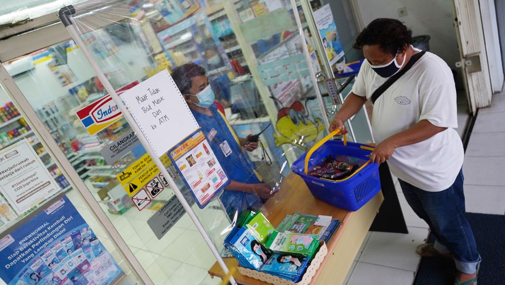Petugas minimarket di RT 003 RW 003, Cilangkap, Jakarta Timur, melayani pembeli yang hanya di luar ruang terkait penyebaran Covid-19 di wilayah ini, Minggu (23/5/2021). 