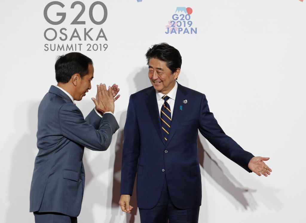 Presiden Indonesia Joko Widodo (kiri) disambut oleh Perdana Menteri Jepang Shinzo Abe pada saat kedatangannya untuk sesi foto keluarga di KTT G20 di Osaka pada 28 Juni 2019.