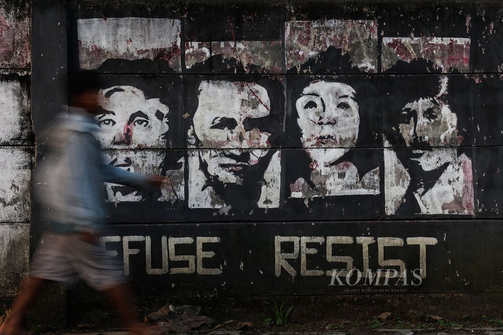 A man crosses in front of a mural of fighters and human rights activists (HAM) in the Bojongsari area, Depok, West Java, Tuesday (23/8/2022). President Joko Widodo at the MPR Annual Session, 16 August 2022 said that he had signed a Presidential Decree on the Formation of a Team for the Non-judicial Resolution of Past Gross Human Rights Violations.