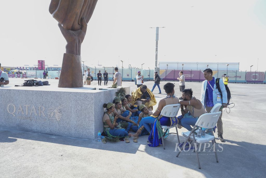 Seniman yang menghibur penonton Piala Dunia 2022 antara Argentina melawan Arab Saudi, berteduh di bayangan sebuah patung yang ada di sekitar Stadion Lusail, Qatar, Selasa (22/11/2022). 