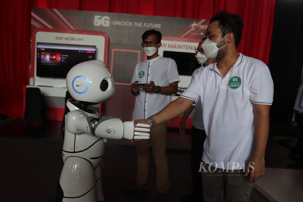 Petugas bersalaman dengan UU Robot yang dijalankan melalui jaringan 5G saat peluncuran layanan 5G Telkomsel di Jakarta, 27 Mei 2021. 