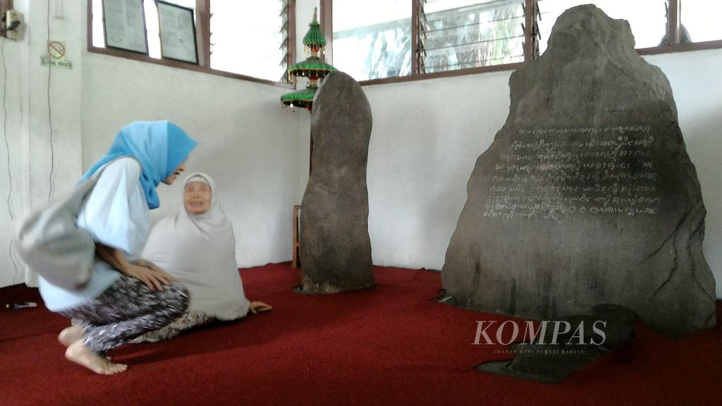 Maemunah (75) yang berkerudung putih menerima pengunjung Prasasti Batu Tulis, Kota Bogor, Jumat (31/7/2015). Prasasti Batu Tulis merupakan bukti otentik keberadaan Kerajaan Pajajaran yang berpusat di wilayah yang saat ini adalah Kota Bogor.