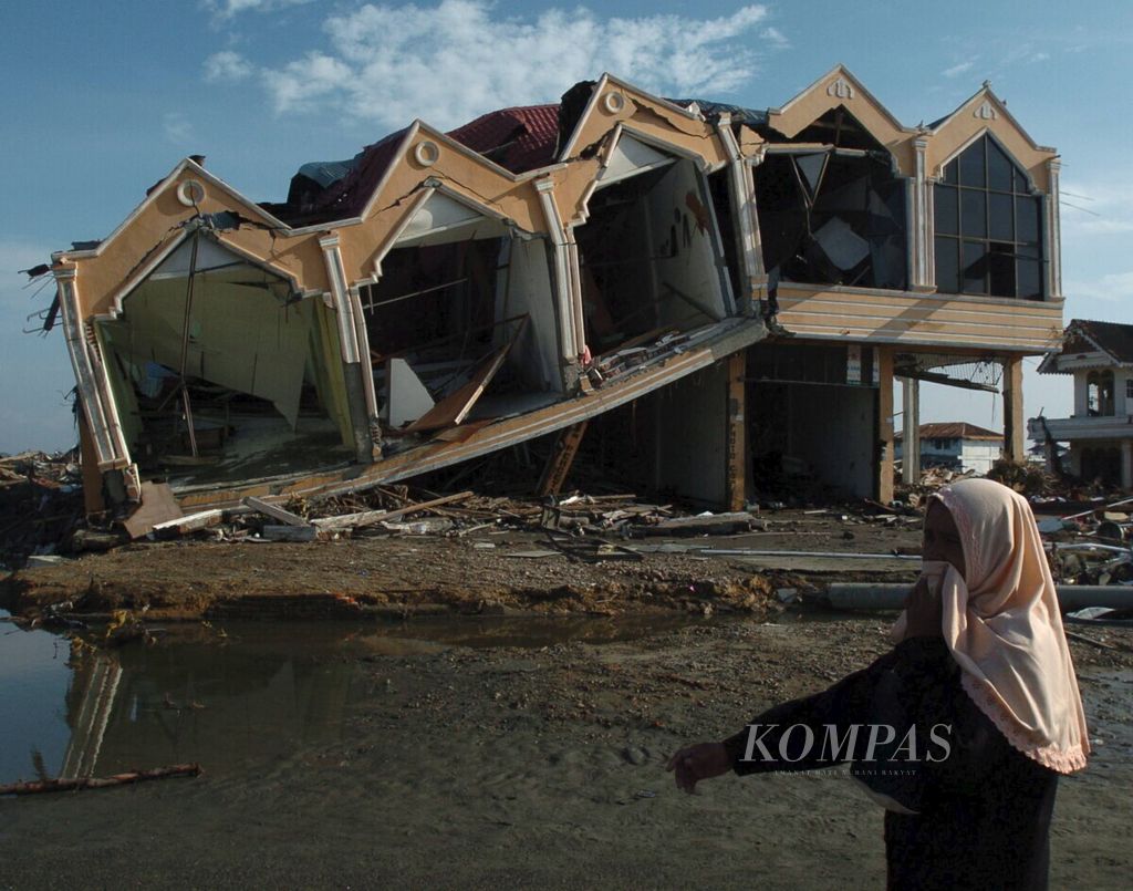 Warga melintas di permukiman yang hancur tersapu gempa dan tsunami di Lampare Kota, Banda Aceh, Provinsi Nanggroe Aceh Darussalam, Selasa (28/12).