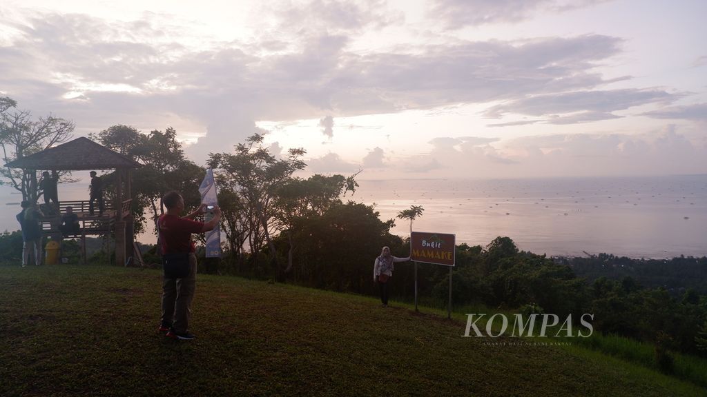 Pengunjung berfoto saat menikmati matahari terbit di puncak Bukit Mamake di Desa Sarang Tiung, Kecamatan Pulau Laut Sigam, Kabupaten Kotabaru, Kalimantan Selatan, Rabu (6/7/2022). 