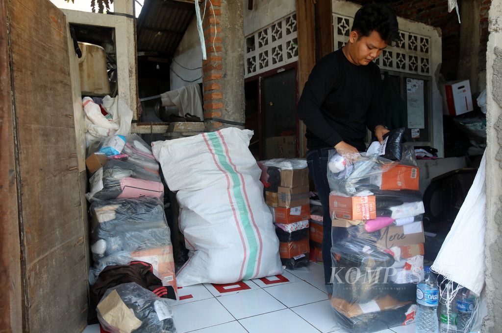 Rio (23), kurir ekspedisi, bersiap mengantarkan barang dari titik pengedropan logistik barang dari gudang (<i>base camp </i>kurir) di kawasan Cipinang Jaya, Jakarta, Rabu (6/4/2022). Dalam sehari, seorang kurir dapat mengantar hingga sekitar 100 item barang berbagai dimensi. Kurir mengambil barang dari lokasi ini untuk diantar ke alamat pelanggan. 