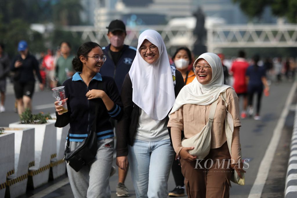 Remaja putri tertawa di sela-sela perbincangan saat mereka jalan santai di kawasan bebas kendaraan bermotor di Jakarta, akhir Mei 2023.