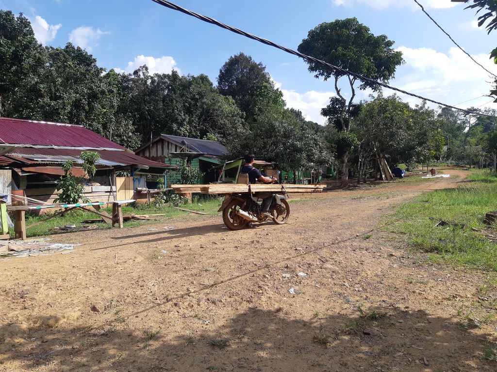 Seorang warga membawa kayu untuk membangun rumah di Kampung Mului, Desa Swan Slotung, Kecamatan Muara Komam, Kabupaten Paser, Kalimantan Timur, Rabu (22/11/2023).