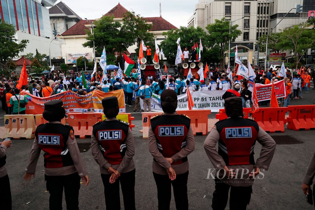 Polisi berjaga di depan massa aksi buruh saat menuntut kenaikan upah tahun 2024 di Jalan Pahlawan, Kota Semarang, Jawa Tengah, Kamis (30/11/2023).  