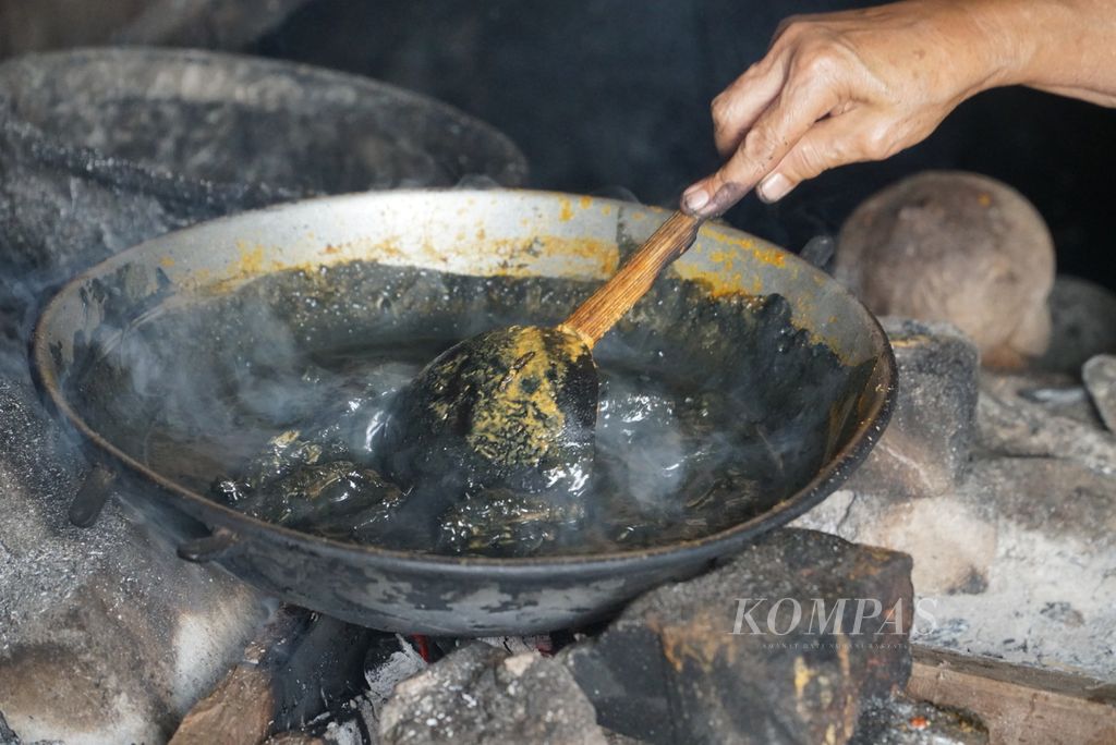Rasuhatni (69) memasak gulai ayam galundi di rumahnya, Nagari Sulit Air, Kecamatan X Koto Diatas, Kabupaten Solok, Sumatera Barat, Kamis (26/5/2022). Gulai khas Sulit Air ini berwarna hitam karena dicampur bubuk buah galundi.