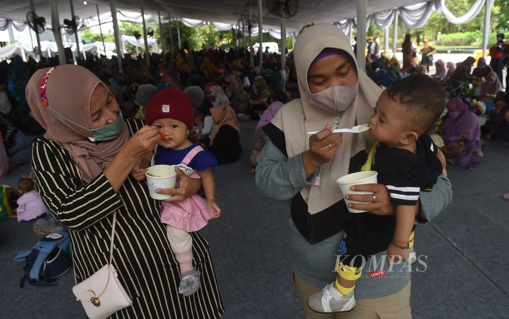 Ibu memberi makan bayinya dengan bubur sehat saat peluncuran Gebyar Lomba Balita Sehat di halaman Balai Kota Surabaya, Jawa Timur, Rabu (26/1/2022). 