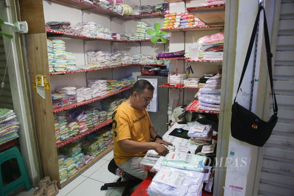 Kosim, pedagang pakaian bayi, mempersiapkan barang yang terjual melalui lokapasar di Pasar Rumput, Jakarta Selatan, Kamis (24/1/2024). Kosim mengakui beralih berjualan melalui lokapasar pada masa pandemi Covid-19 tahun 2020. 