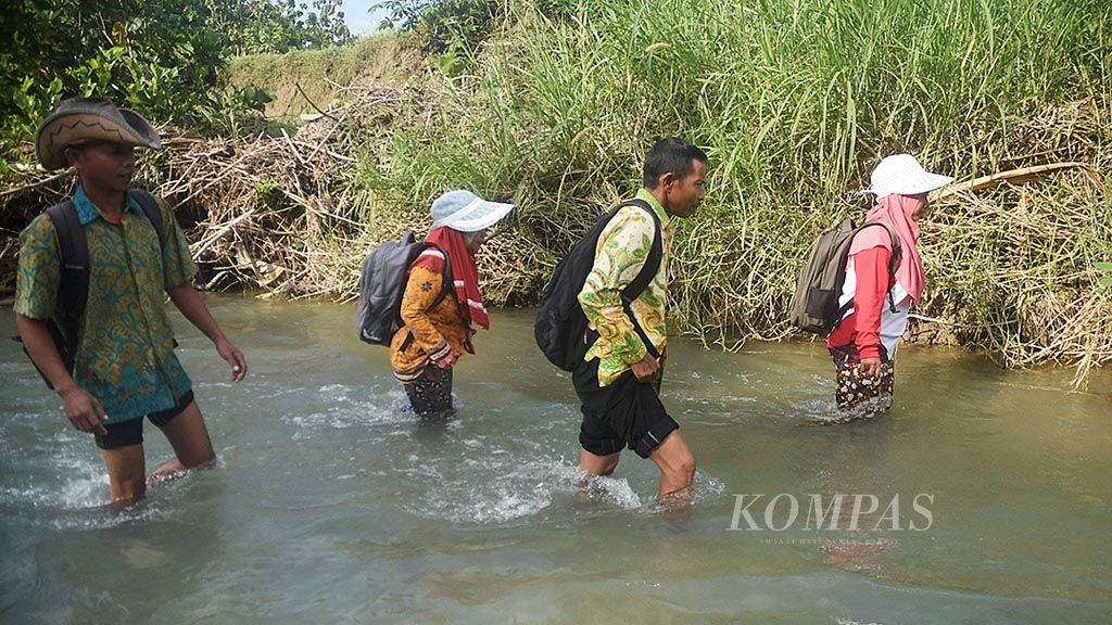 Guru SD Negeri Pojokklitih 3, Kecamatan Plandaan, Jombang, (dari kiri ke kanan) Sucipto, Laila Maulida, Trisno, dan Nurmala Sari, menyeberangi sungai untuk mengajar, Kamis (23/3). 