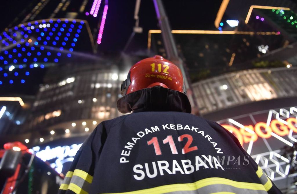 Petugas melihat rekan mereka yang ada di <i>sky lift </i>melakukan pembasahan di Tunjungan Plaza yang mengalami kebakaran, Kota Surabaya, Jawa Timur, Rabu (13/4/2022). 