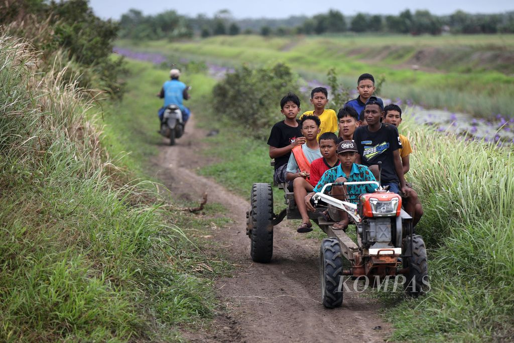 Anak-anak berkeliling areal persawahan menggunakan traktor yang digunakan untuk menarik gerobak yang mereka tumpangi di Kampung Waninggap Kai, Distrik Semangga, Kabupaten Merauke, Papua Selatan, Selasa (23/7/2024). 