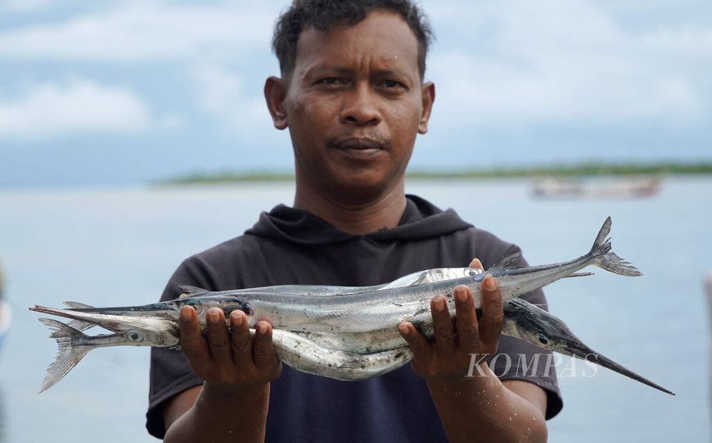 Emon Mau (30) menunjukkan ikan sako hasil tangkapannya di kampung nelayan Pulau Doom, Kota Sorong, Papua Barat Daya, Minggu (11/6/2023).