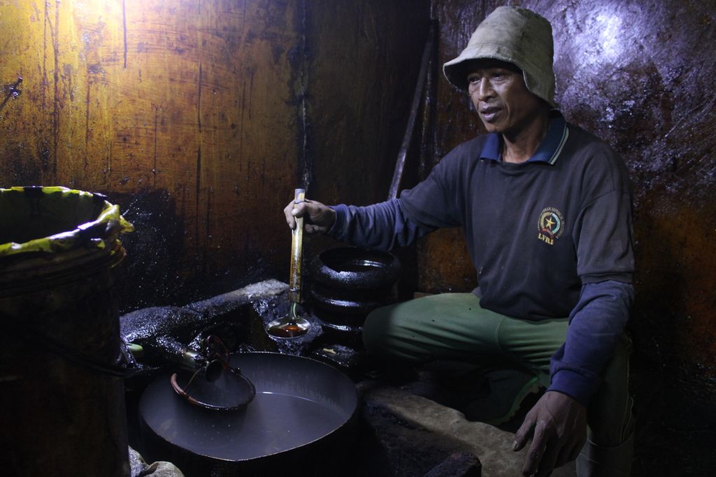 Salah satu pekerja mengecek minyak akar wangi atau vetiver di salah satu ruangan pabrik penyulingan, Desa Sukahati, Kecamatan Cilawu, Kabupaten Garut, Jawa Barat, Jumat (12/1/2024).