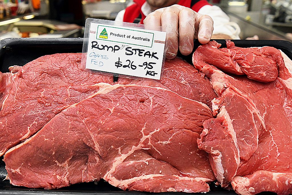 Seorang tukang daging di Australia, George Vourvahakis, mengangkat nampan berisi daging sapi segar di tokonya di Yarraville, pinggiran Melbourne, Selasa (12/5/2020). China menghentikan sementara impor dari empat pemasok daging sapi utama Australia.