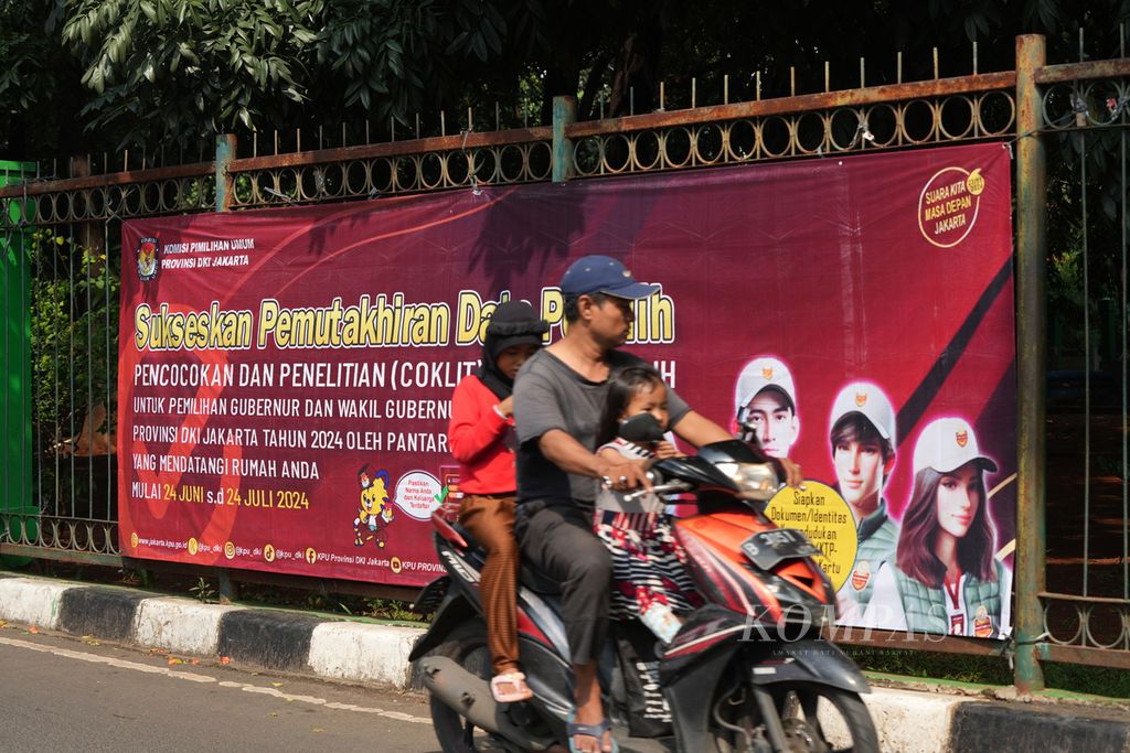 Warga melintas di depan spanduk Sukseskan Pemutakhiran Data Pemilih (Pantarlih) di Cakung, Jakarta Timur, Selasa (9/7/2024). 