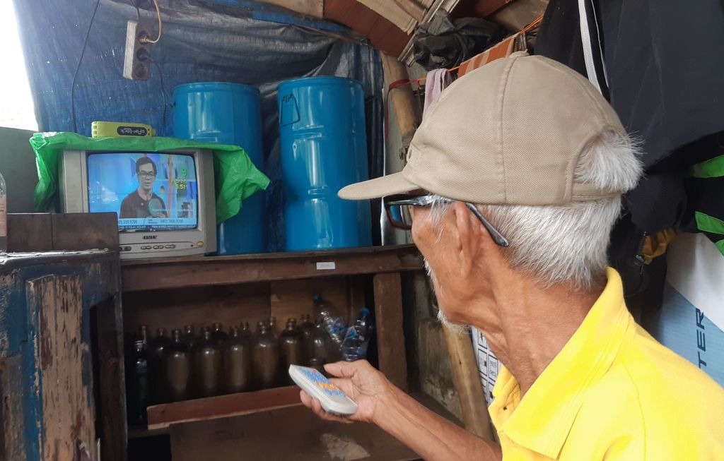 Raharjo (78), warga RT 008 RW 004 Kelurahan Palmerah, Palmerah, Jakarta Barat, saat menonton tayangan televisi di kios bensinnya, Minggu (14/3/2021) siang. Terlalu lama menonton televisi meningkatkan risiko mengalami pembekuan darah.