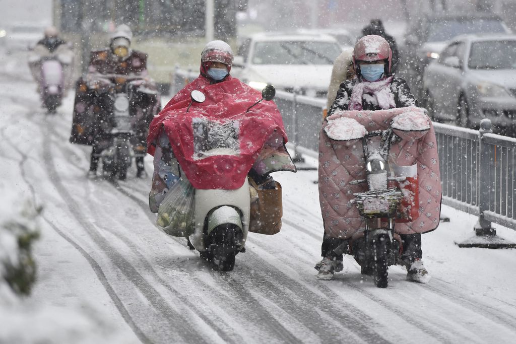 Warga mengendarai skuter menembus hujan salju lebat di Huai'an, Provinsi Jiangsu, China, Minggu (4/2/2024).