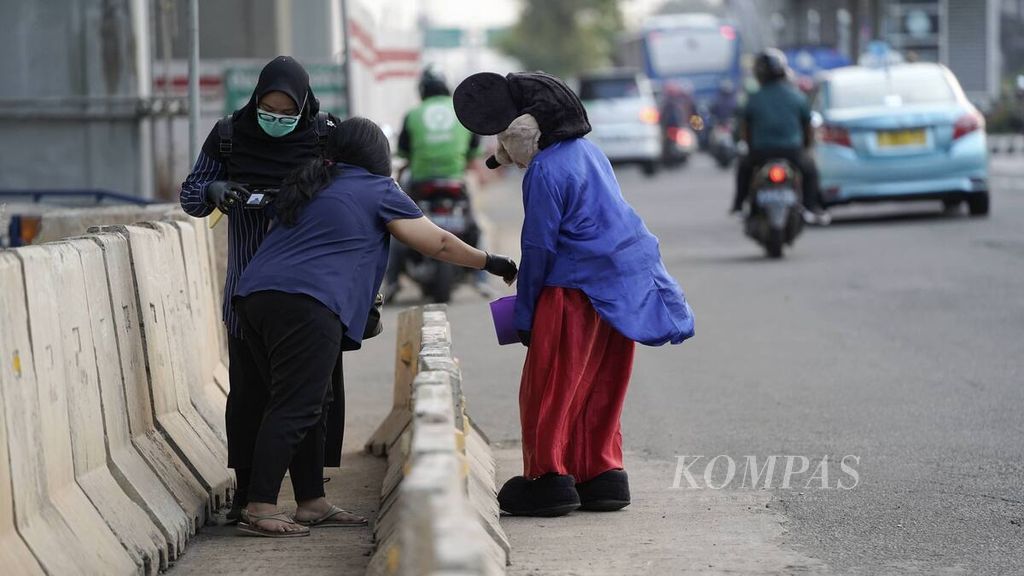 Pejalan kaki memberi uang kepada badut Mickey Mouse yang berjalan gontai di Jalan MT Haryono, Jakarta Timur, Rabu (8/7/2020). 