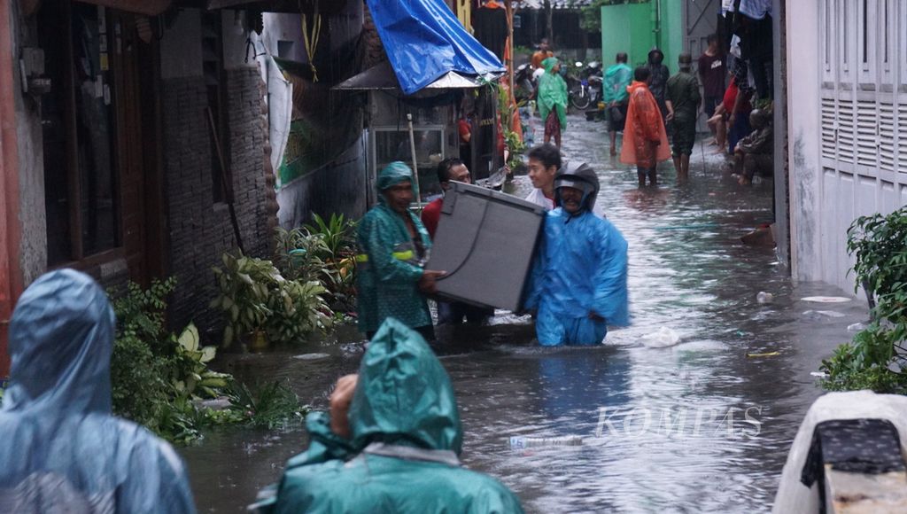 Warga menggotong barang berharganya sewaktu terjadi banjir di Kelurahan Jagalan, Kecamatan Jebres, Kota Surakarta, Jawa Tengah, Kamis (16/2/2023). Banjir terjadi akibat hujan deras berjam-jam. 