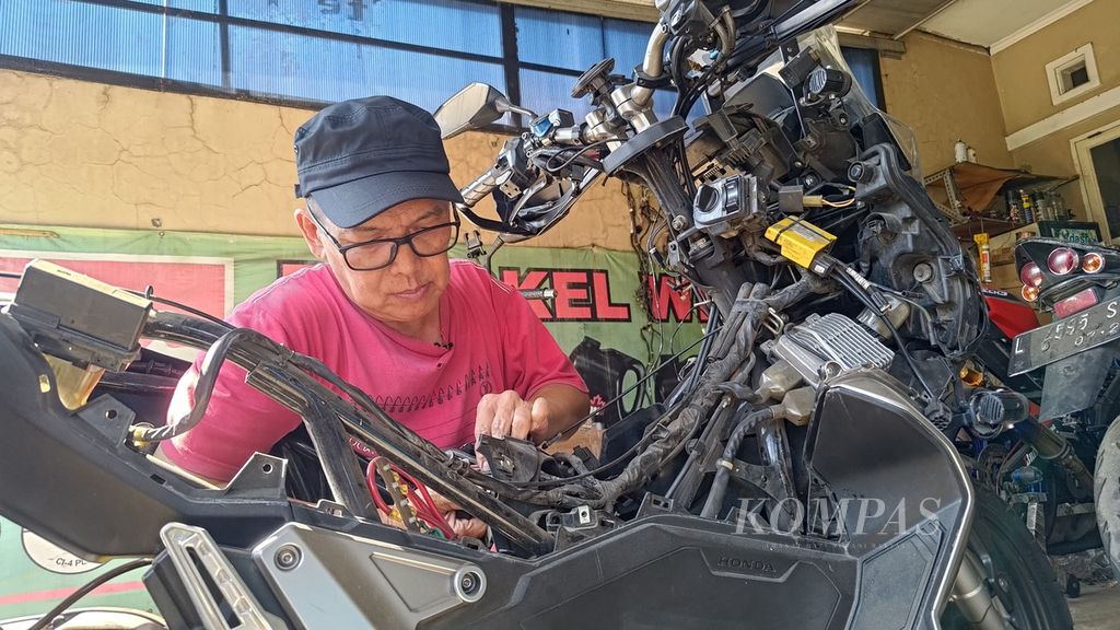 Kam Wie Tiong (60) sedang berkutat dengan sistem perkuncian sepeda motor di bengkelnya, di Tangerang, Banten, Selasa (12/9/2023).