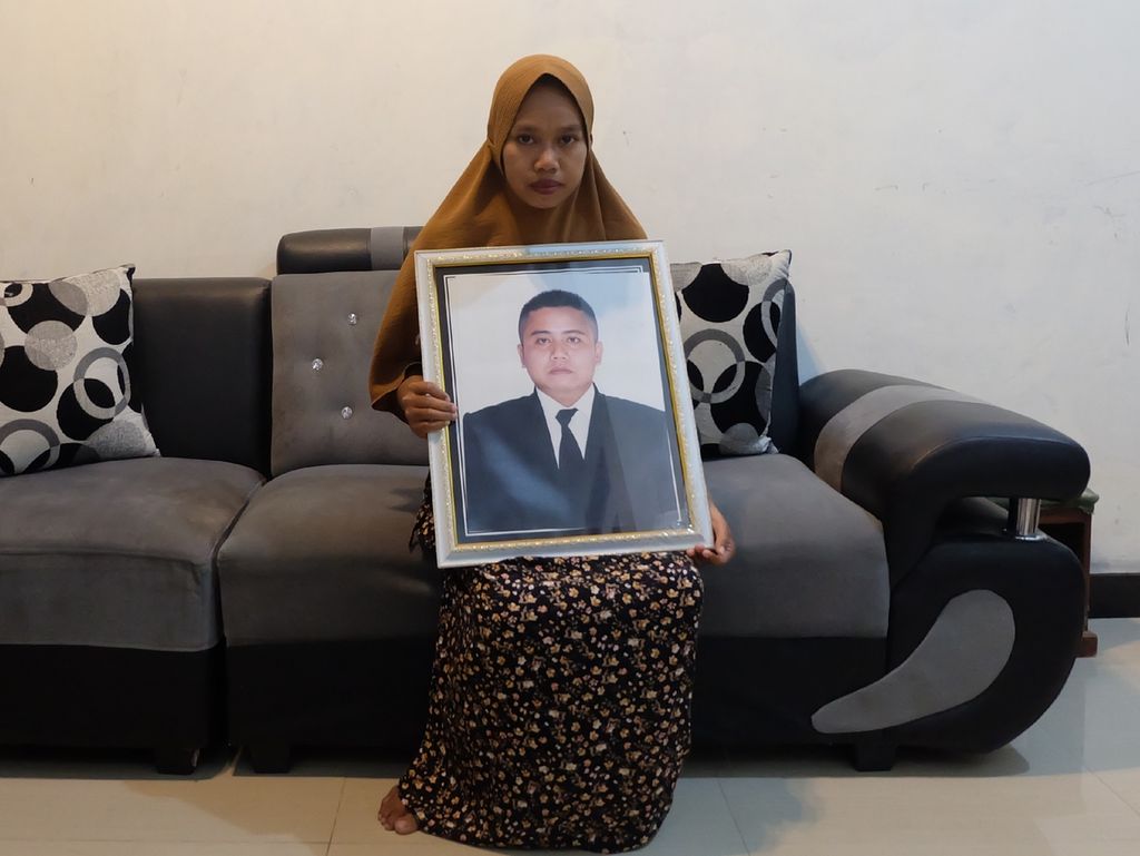 Sri Rahayu (28) memegang foto suaminya, almarhum Warnoko (34), di rumahnya di Kecamatan Larangan, Kabupaten Brebes, Jawa Tengah, Rabu (26/7/2023). Warnoko meninggal karena sakit saat dalam kontrak kerja sebagai anak buah kapal ikan Korea Selatan.