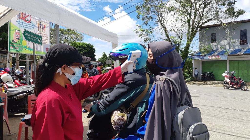 Petugas memeriksa suhu warga di perbatasan Kota Ambon dan Kabupaten Maluku Tengah. Kota Ambon, Maluku, resmi memberlakukan Pembatasan Kegiatan Masyarakat pada Senin (8/6/2020).