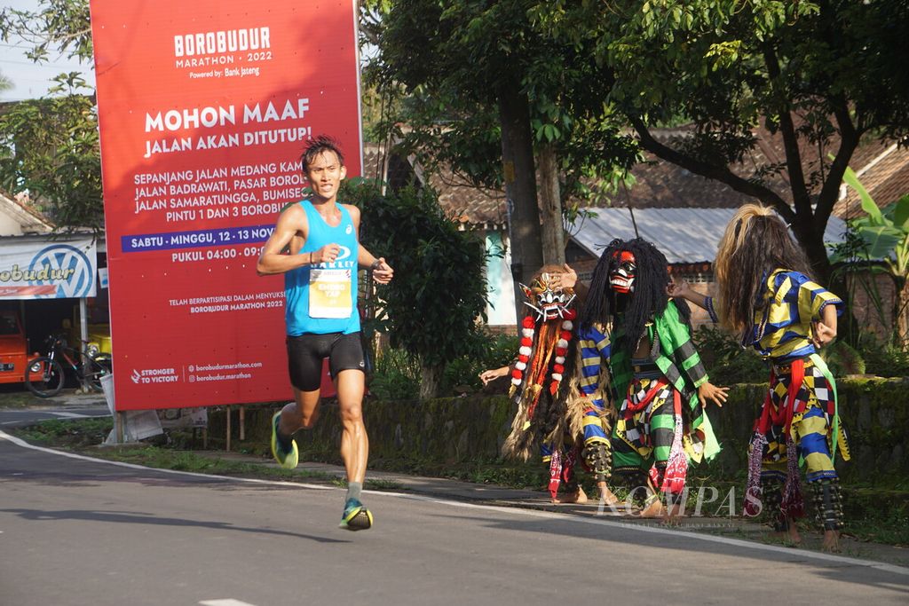 Hendro Yap, a runner for Elite Race Borobudur Marathon 2022 Powered by Bank Jateng, passes between the Rampak Buto dancers in the Borobudur Temple Area, Magelang, Central Java, Saturday (12/11/2022.