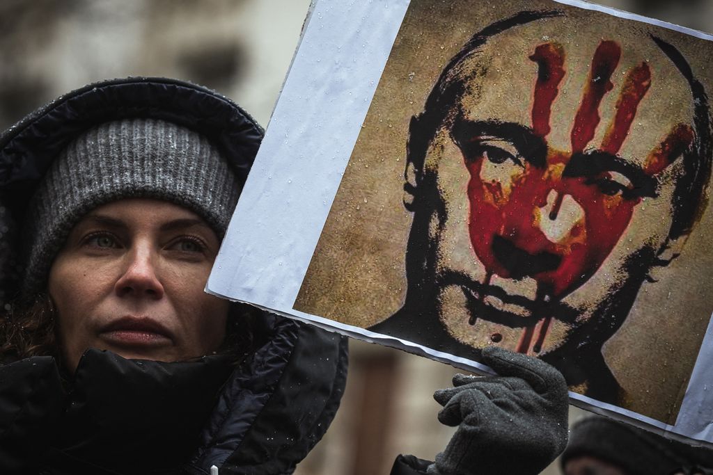 Pengunjuk rasa memegang plakat bergambar Presiden Rusia Vladimir Putin saat demonstrasi menentang invasi militer Rusia di Ukraina, di Beograd, Serbia, 6 Maret 2022. 