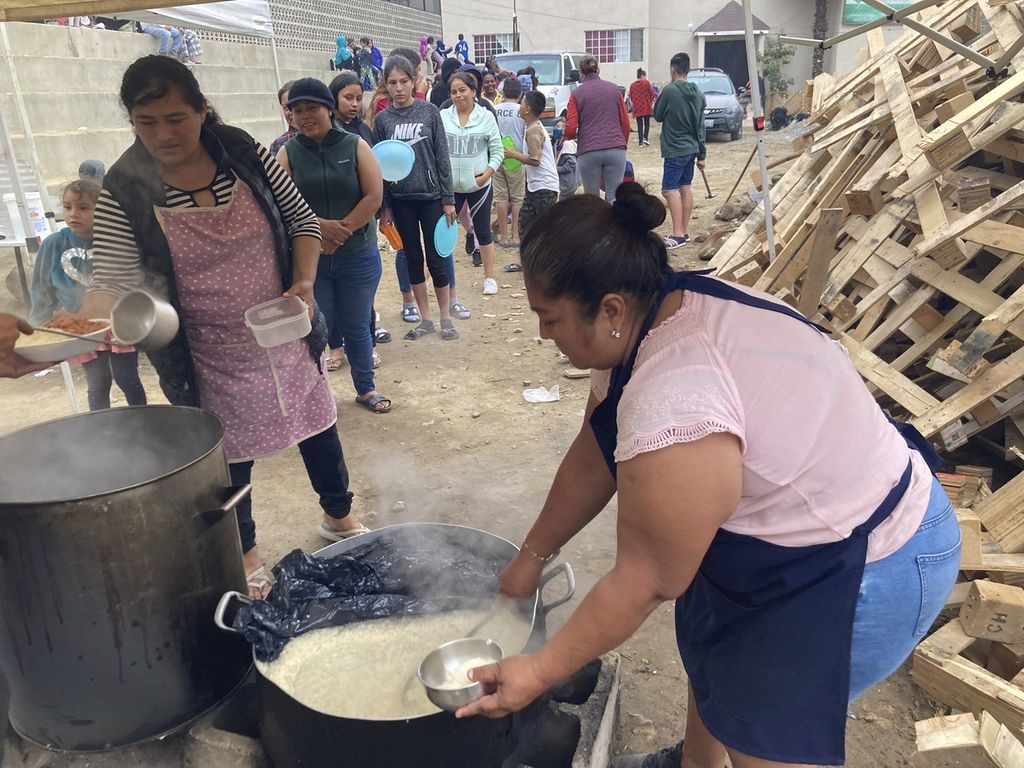 Seorang perempuan melayani pemberian makan malam berupa nasi dan kacang-kacangan kepada para migran di pusat penampunagan Templo Embajadores de Jesus, Tijuana, Meksiko, 13 Oktober 2022. 
