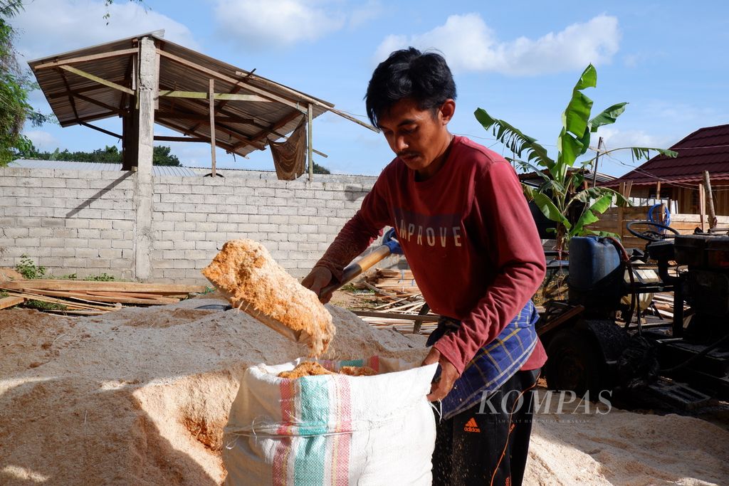 Warga mengambil upah dengan mengisi serbuk kayu ke dalam karung di daerah Lembah Sempage, Narmada, Lombok Barat, Nusa Tenggara Barat, Senin (11/10/2021). Serbuk kayu tersebut kemudian didistribuskan ke PLTU Jeranjang di Desa Taman Ayu, Gerung, Lombok Barat. Sejak akhir 2020, PLN UIW NTB mulai mendorong penggunaan biomassa, seperti sampah dan serbuk kayu, sebagai substitusi batubara di PLTU Jeranjang. Namun, pasokan biomassa masih terbatas bahkan belum mampu memenuhi kebutuhan 3 persen (sekitar 45 ton) seluruh unit PLTU Jeranjang yang berkapasitas 3x25 megawatt.