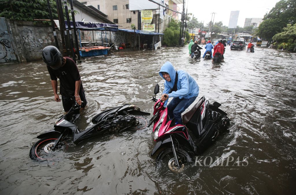 Pengendara sepeda motor terjatuh saat menembus banjir yang merendam Jalan HOS Cokroaminoto, Ciledug, Kota Tangerang, Banten, Jumat (22/3/2024).  
