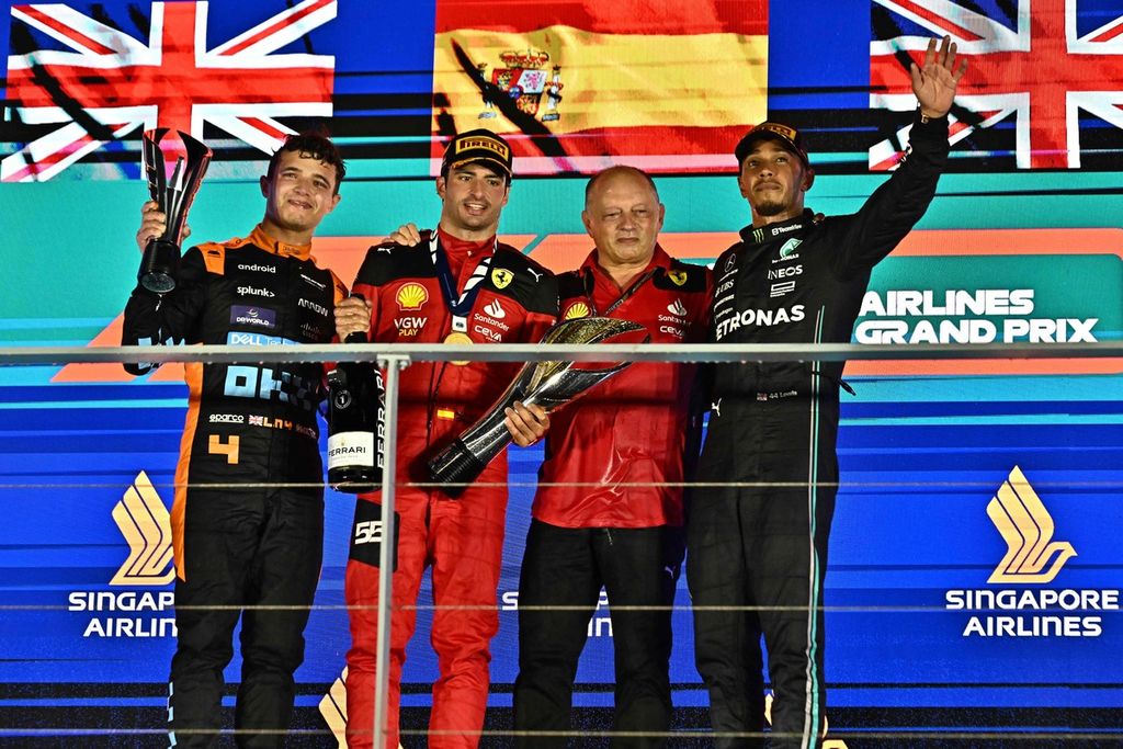 Para pemenang balapan Grand Prix Formula 1 seri Singapura di Sirkuit Jalan Raya Marina Bay, Singapura, Minggu (17/9/2023), berpose di atas podium. Mereka adalah pebalap tim Ferrari, Carlos Sainz Jr, yang finis pertama (kedua dari kiri); pebalap McLaren, Lando Norris (kiri), yang finis kedua; dan pebalap Mercedes, Lewis Hamilton (kanan), yang finis ketiga. Mereka berpose bersama ketua tim Ferrari, Frederic Vasseur (kedua dari kanan). 