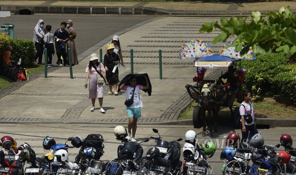 Pengunjung berada di sekitar kawasan salah satu pintu masuk Monas, Jakarta Pusat, saat siang hari, Senin (24/4/2023). Dalam beberapa waktu terakhir cuaca di Jakarta dan wilayah lainnya di Indonesia terasa panas dengan kisaran suhu maksimum siang hari mencapai 35-37,5 derajat celsius. 