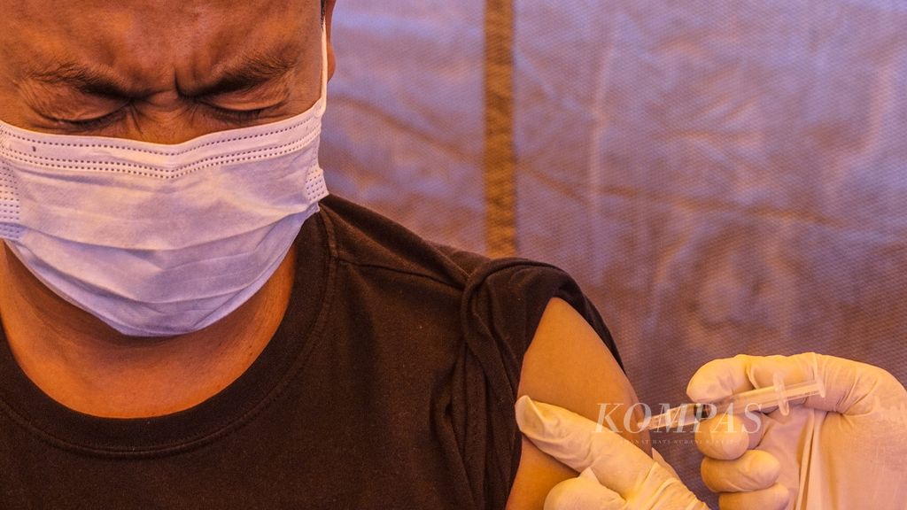 Ekspresi seorang warga ketika disuntik vaksin Covid-19 dosis ketiga di tenda Sentra Vaksin Kecamatan Bogor Selatan di halaman Taman Makam Pahlawan Bondongan, Kota Bogor, Jawa Barat, Rabu (23/2/2022).