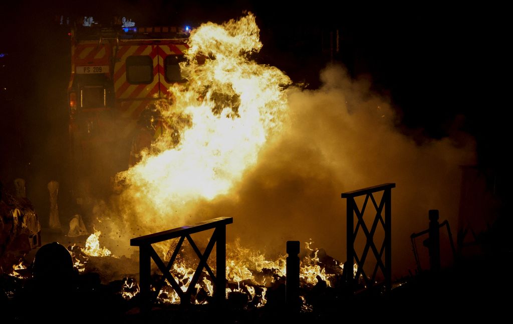 Petugas pemadam kebakaran berupaya memadamkan api dari sebuah mobil yang dibakar saat protes massa di Nanterre, sebelah barat Paris, Perancis, pada 29 Juni 2023 dini hari. Kerusuhan melanda sejumlah kota di Perancis menyusul penembakan seorang remaja oleh polisi. 