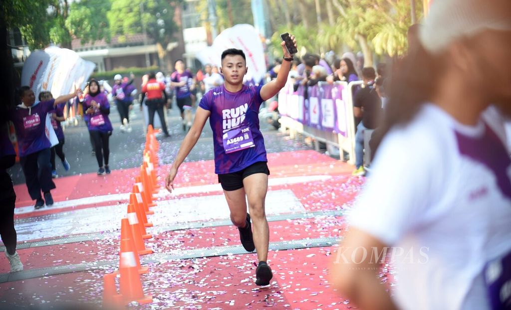 Pelari memasuki garis finis pada RUNHUB di Balai Kota Surabaya, Surabaya, Minggu (8/10/2023). Lomba lari RUNHUB diikuti oleh 2.000 pelari. RUNHUB diselenggarakan oleh Kementerian Perhubungan bekerja sama dengan harian <i>Kompas</i> dan didukung BOOK Cabin yang merupakan bagian Lion Group. 